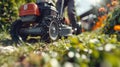 Close-up of a lawnmower cutting grass in a garden, with a person operating the machine