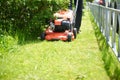 A close-up lawnmower mows the green grass on the lawn.Bright Sunny day Royalty Free Stock Photo