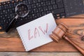 Close-up laws words written on spiral notepad gavel and magnifying glass on the keyboard.