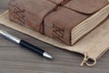 Close-up of leather-bound book on wooden board with pen Royalty Free Stock Photo