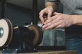 Close up of leather craftsman sharpens knife for cutting leather on sander. Handmade concept. Concept of small business to create