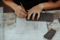 Close up of leather craftsman working with natural leather using tools. Handmade master at work in local workshop