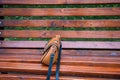 A close-up of a leather fashionable lady`s bag, made in brown color. She is standing on an old bench in a summer park Royalty Free Stock Photo