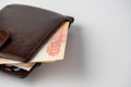 A close-up of a leather wallet full of 5000 rubles banknotes lies on a white background. Side view, copy space Royalty Free Stock Photo