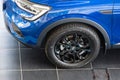 Close-up of left front wheel and left front headlight of blue SUV Renault Arkana car. Showroom in Renault dealership.