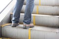 Close up leg of Men wear jeans, leather shoes. Standing on the escalator