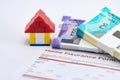 Close up of a lego house near money bundles on home insurance form