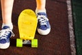 Close up legs in blue sneakers riding on yellow skateboard in motion. Active urban lifestyle of youth, training, hobby, activity