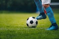 Close up of legs and feet of football player in blue socks and shoes running and dribbling with the ball Royalty Free Stock Photo