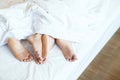 Close up legs feet of two Lovers couple sleeping side by side embracing under blanket white sheets in bed at home on holiday conc Royalty Free Stock Photo