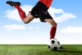 Close up legs of football player in red socks and black shoes running and kicking the ball in free kick action playing outdoors Royalty Free Stock Photo