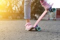 Close-up legs girl skateboarder blue jeans and pink sneakers riding pink penny skate longboard.