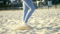 Close-up of the legs of a girl in tight clothes and white socks walks on the sand