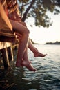 Close-up of legs of a group of female friends in bikini sitting on the dock on the river. Summer, river, vacation