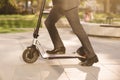 Close up of legs man in suit riding electric scooter in city. Unknown businessman in classic suit ride on electric