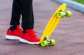 Close up legs in red sneakers riding on yellow skateboard in motion. Active urban lifestyle of youth, training, hobby,
