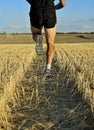 Close up legs and shoes of sport man running cross country back view perspective