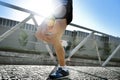 Close up legs and shoes of young athletic man practicing running in urban background natural rising backlight