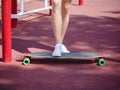 Close-up legs on a skateboard. Man standing on a trendy longboard on a blurred park background. Skateboarding concept.
