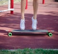 Close-up legs on a skateboard. Man standing on a trendy longboard on a blurred park background. Skateboarding concept.