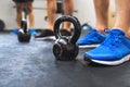 A close-up of legs of three men in gym standing by kettlebells.