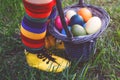 Close-up of legs of toddler girl with colorful stockings and shoes and basket with colored eggs. Child having fun with Royalty Free Stock Photo