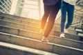 Close up legs of two traveling people walking on stepping up stair in modern city. Sneakers and jeans elements. Business and Royalty Free Stock Photo