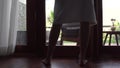 Close-up of legs of woman in bathrobe unveil curtain, standing near the window in home.