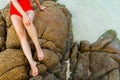 Close up of a legs of woman in swimsuit sitting on stone rock at sea beach Royalty Free Stock Photo