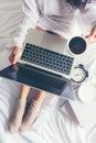 Close up legs women on white bed in the bedroom. Women reading book and drinking coffee in morning relax mood in winter season Royalty Free Stock Photo