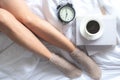 Close up legs women on white bed.  Women reading book and  drinking  coffee in morning relax mood in winter season. Royalty Free Stock Photo