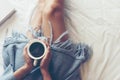 Close up legs women on white bed in the bedroom. Women reading book and drinking coffee in morning relax mood in winter season. Royalty Free Stock Photo