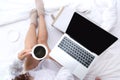 Close up legs women on white bed in the bedroom. Women reading book and drinking coffee in morning relax mood in winter season Royalty Free Stock Photo