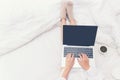 Close up legs women on white bed in the bedroom. Women working on laptop