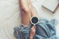Close up legs women on white bed. Women reading book and drinking coffee in morning relax mood in winter season. Royalty Free Stock Photo