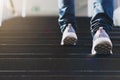 Close up legs of young businessman while walking up the stairs in the modern city with the sunspot background. Go up, success, Royalty Free Stock Photo