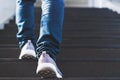 Close up legs of young businessman while walking up the stairs in the modern city with the sunspot background. Go up, success, Royalty Free Stock Photo