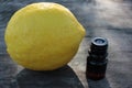 Lemon essential oil in a small bottle and whole lemon fruit on rough wooden background Royalty Free Stock Photo