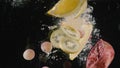 Close up of lemon, kiwi slices, grapes and half of pomegranate thrown in the water  on black background. Action Royalty Free Stock Photo