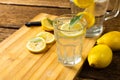 Close-up of lemonade in jug and drinking glass with lemons and leaves on cutting board over table Royalty Free Stock Photo