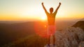 LENS FLARE: Male tourist celebrates reaching top of the mountain at sunrise.