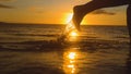 CLOSE UP, LENS FLARE: Small water droplets fly off female jogger`s feet running at breathtaking sunset.