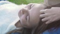Close-up of lesbians relaxing in park on grass. Media. Woman`s hand stroking head of woman lying on her lap. Tenderness