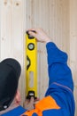 Close-up of a level for leveling a wooden surface in the hands of a worker in a blue uniform