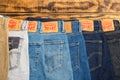 Close-up of Levi`s jeans for sale. Row of multi-colored branded pants. selective focus. On a wooden background. Space for text