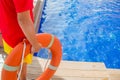 Close-up of a lifeguard`s hand grabbing a lifebuoy ring and watching over a swimming pool - Concept of lifeguard at work Royalty Free Stock Photo