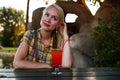 Close up lifestyle portrait of cute stylish young woman posing outdoor, sitting in summer cafe and drinking exotic cocktail. Royalty Free Stock Photo