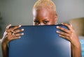 Close up lifestyle portrait of young classy attractive and happy black african american woman posing playful hiding behind laptop