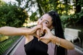 Close up lifestyle portrait of young pretty Asian woman with charming smile, wearing black trendy clothes, making heart Royalty Free Stock Photo