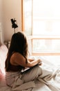 Close up lifestyle of pretty young woman looking out the window sitting on her cozy bed and making notes to her diary. Fall season Royalty Free Stock Photo